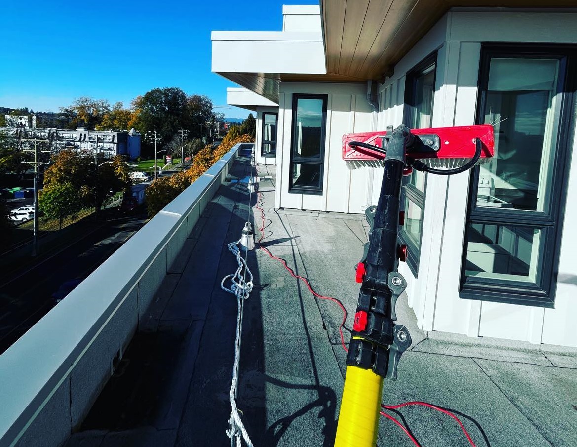 Tucker window cleaning pole being used on a rooftop to clean windows of a commercial building.